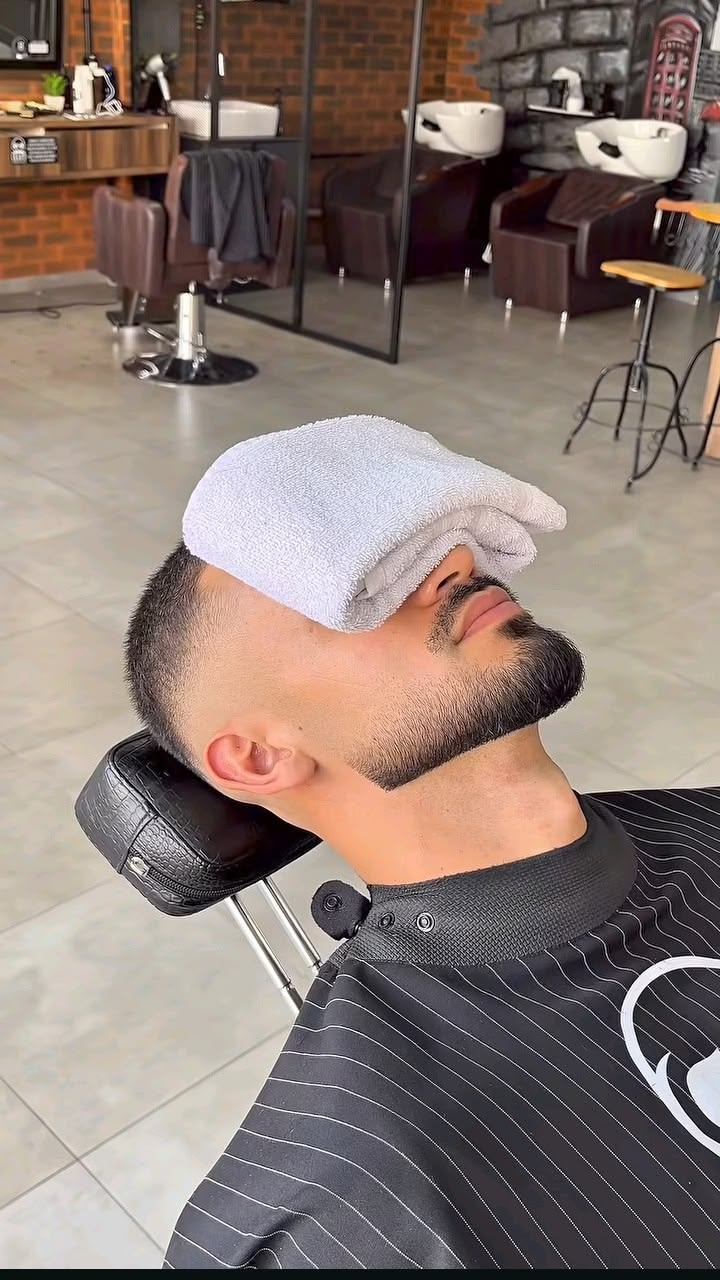 A client relaxing with a hot towel during a straight razor shave
