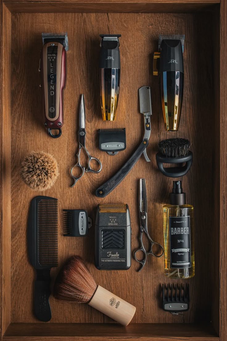 A barber's tool kit laid out in a wooden case with clippers, trimmers, scissors, a straight razor, and brushes