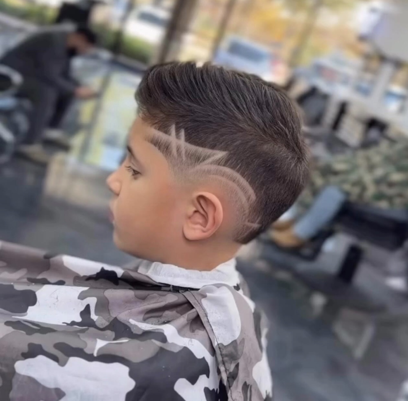A young client with a comb over and a freestyle star design shaved into the fade