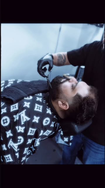 A barber detailing a full beard with scissors