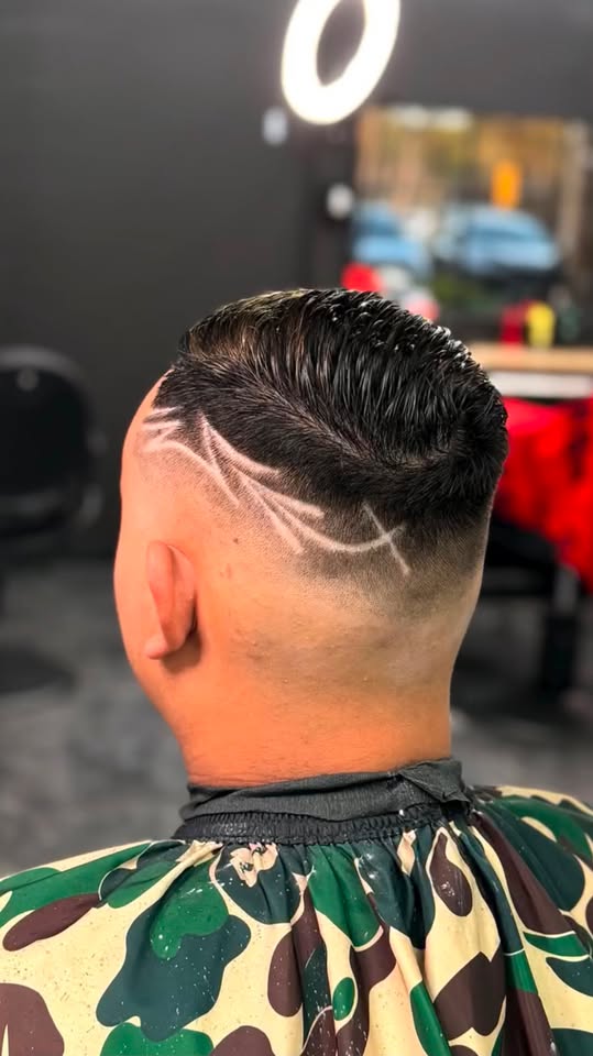 A freestyle design shaved into a slicked back fade