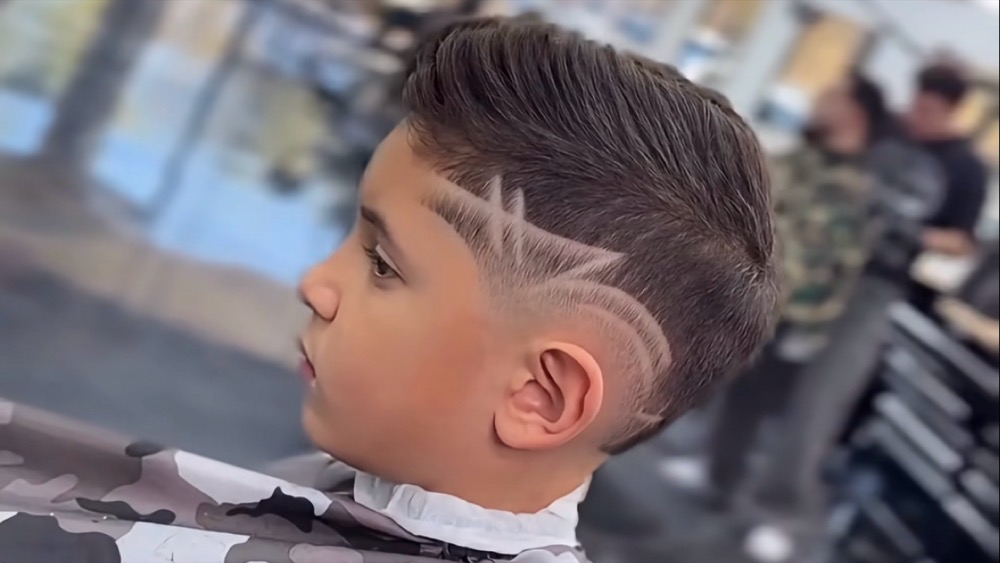 A freestyle design shaved into a kids comb over fade
