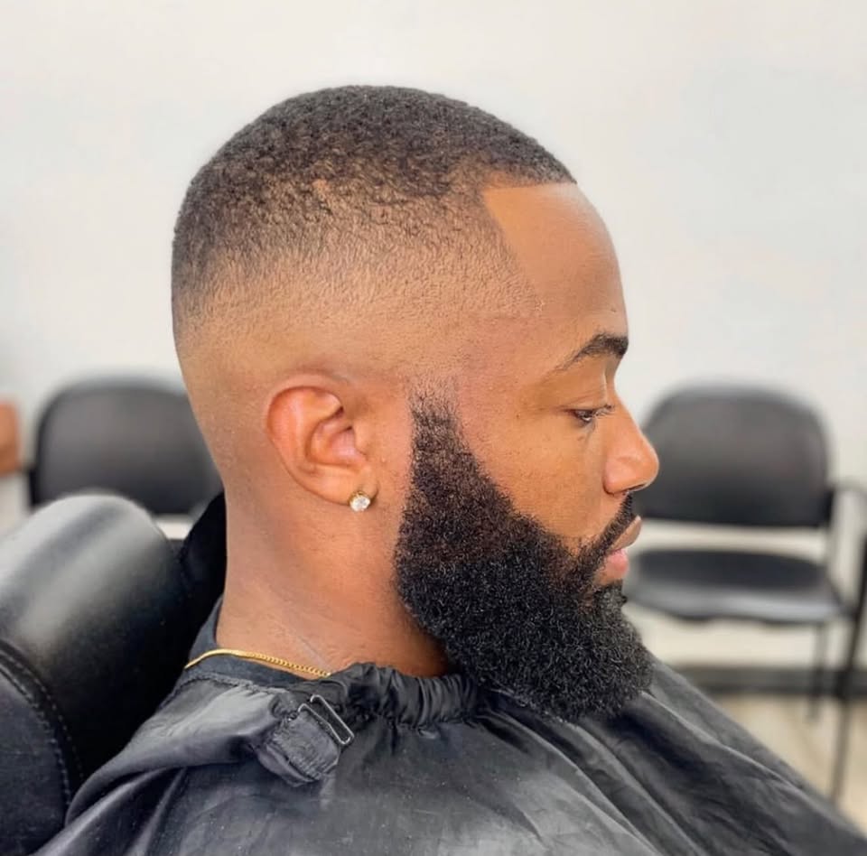 A full sculpted beard with a bald fade